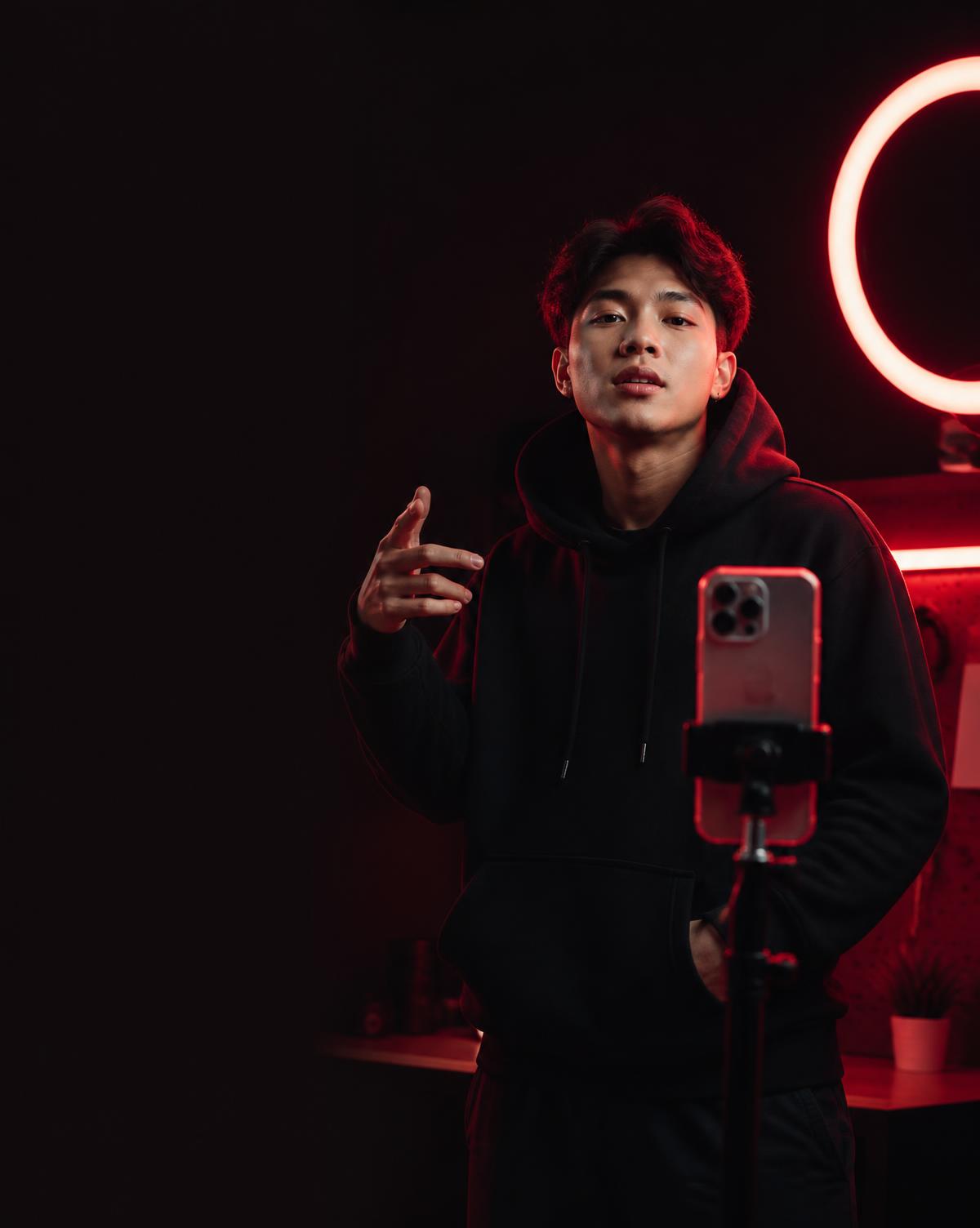 TikTok creator filming in a black studio lit by fire-red lights